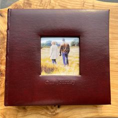 an image of a couple holding hands in a leather frame on top of a wooden table