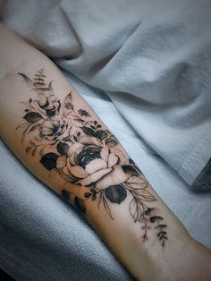 a woman's arm with black and white flowers on the left side of her body