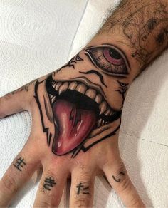 a man's hand with tattoos on it and an evil face painted on the palm