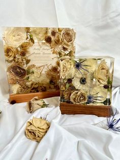 two vases with dried flowers in them on a white sheet