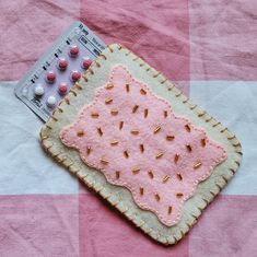 a pink and white checkered table cloth with an embroidered piece of fabric on it