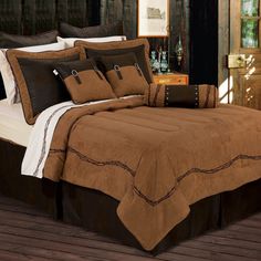 a bed with brown and white comforters on top of it in front of a wooden wall