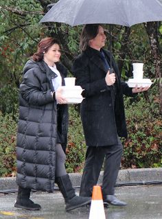 two people walking in the rain holding coffee cups