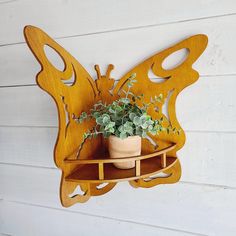 a wooden butterfly shaped shelf holding a potted plant