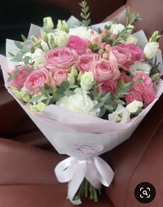 a bouquet of pink and white flowers sitting on top of a car seat