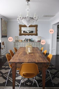 a dining room table with yellow chairs and a chandelier hanging from the ceiling