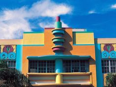 the front of a multi - colored building with an odd looking sculpture on it's side