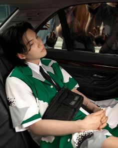 a woman sitting in the back seat of a car wearing a green and white dress