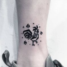 a black and white photo of a rooster tattoo on the ankle