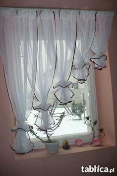 a window with white curtains and flowers on it