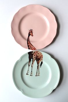 two plates with giraffes painted on them, one pink and one white