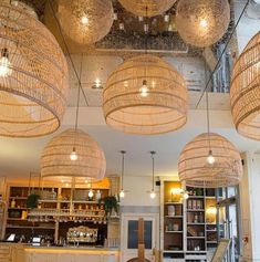 a restaurant with lots of hanging lights above the counter and chairs in front of it