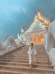 a woman is walking down some stairs in front of a building with dragon statues on it