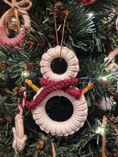 a knitted snowman ornament hanging from a christmas tree