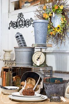 a table topped with lots of pots and pans next to a wall mounted clock