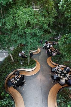 an overhead view of people sitting at tables in the middle of a park with lots of trees