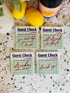 three guest check cards sitting on top of a table next to lemons and wine