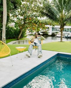 a man sitting on a chair next to a swimming pool