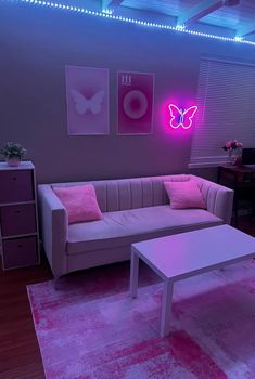 a living room filled with furniture and pink lighting on the ceiling above it is a white coffee table