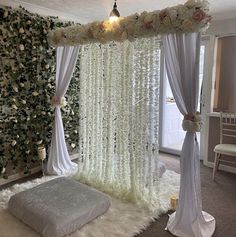 a bed covered in white flowers next to a window with sheer drapes on it