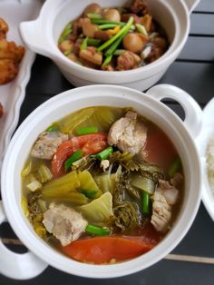 two white bowls filled with soup and vegetables