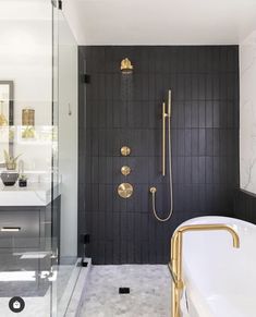 a black and white bathroom with a gold faucet, shower head, and bathtub