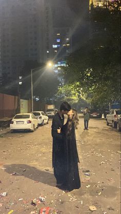 a man and woman kissing in the middle of a street at night with trash all around them