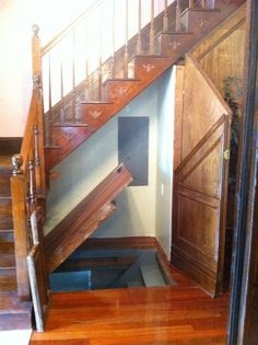 an open door leading up to a wooden stair case in a room with hard wood flooring