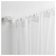 white curtains hanging on the side of a wall next to a window with a remote control