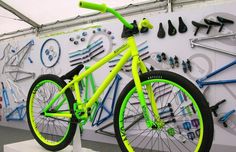 a yellow bicycle is on display in front of a wall with many tools and screwdrivers