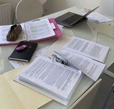 a table topped with books and papers next to a laptop computer on top of a desk