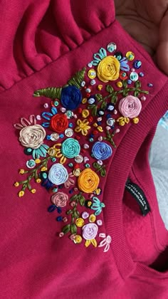 a person holding a pink shirt with colorful flowers on it