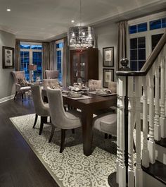 an elegant dining room with chandelier and wooden table surrounded by gray upholstered chairs