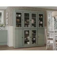 a large green cabinet with glass doors in a dining room next to a table and chairs