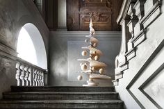 a christmas tree made out of seashells sits on the stairs in an old building