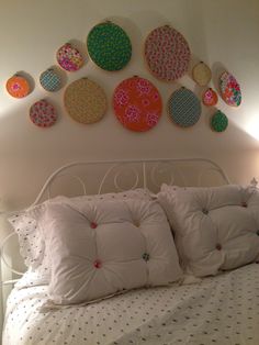 a white bed topped with lots of pillows next to a wall covered in plates on it