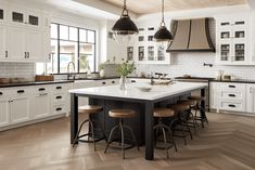 a large kitchen with white cabinets and wooden floors