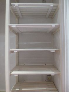 an empty white refrigerator with shelves in it