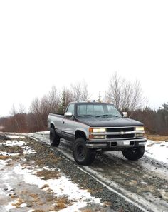 the truck is parked on the side of the road in the wintertime snow covered field