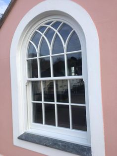 an arched window on the side of a pink building