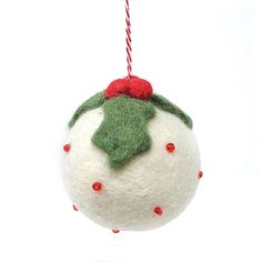 a white ornament hanging from a red and green christmas decoration with holly on top