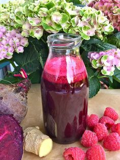 raspberry and ginger juice in a jar next to fresh flowers