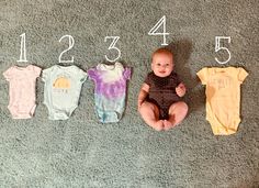 a baby sitting on the floor next to five ones that are numbered in different colors