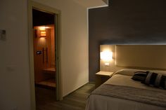 a hotel room with a bed, night stand and lamp on the wall next to it