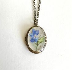 "Gorgeous and perfect for spring, here is a beautiful locket necklace, featuring an oval shaped brass locket which is embellished with a blue violet flower cameo cabochon in the center. This locket is suspended from a soldered brass chain and is closed with a solid brass clasp. Cabochon made from resin. Perfectly sweet, this unique locket necklace comes shipped in a gift box! Locket measures: 7/8\" across x 1 1/4\" long Necklace chain length - please choose from the drop down menu. Locket comes Vintage Pressed Flowers Jewelry Keepsake, Vintage Pressed Flowers Keepsake Jewelry, Handmade Oval Locket Necklace For Keepsake, Handmade Oval Brass Locket Necklace, Blue Violet Flower, Unique Locket Necklace, Unique Locket, Vintage Locket, Vintage Lockets