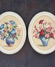 two plates with flowers painted on them are sitting next to each other in front of a wall