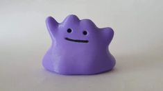 a small purple toy with a smiley face on it's chest and eyes closed