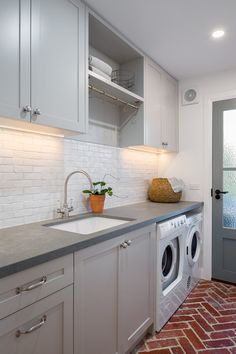 a washer and dryer in a kitchen with brick flooring on the walls