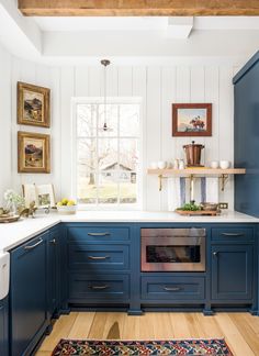 a kitchen with blue cabinets and white counter tops, an area rug on the floor