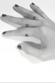 a person's hand with two small stars tattooed on the middle of their fingers